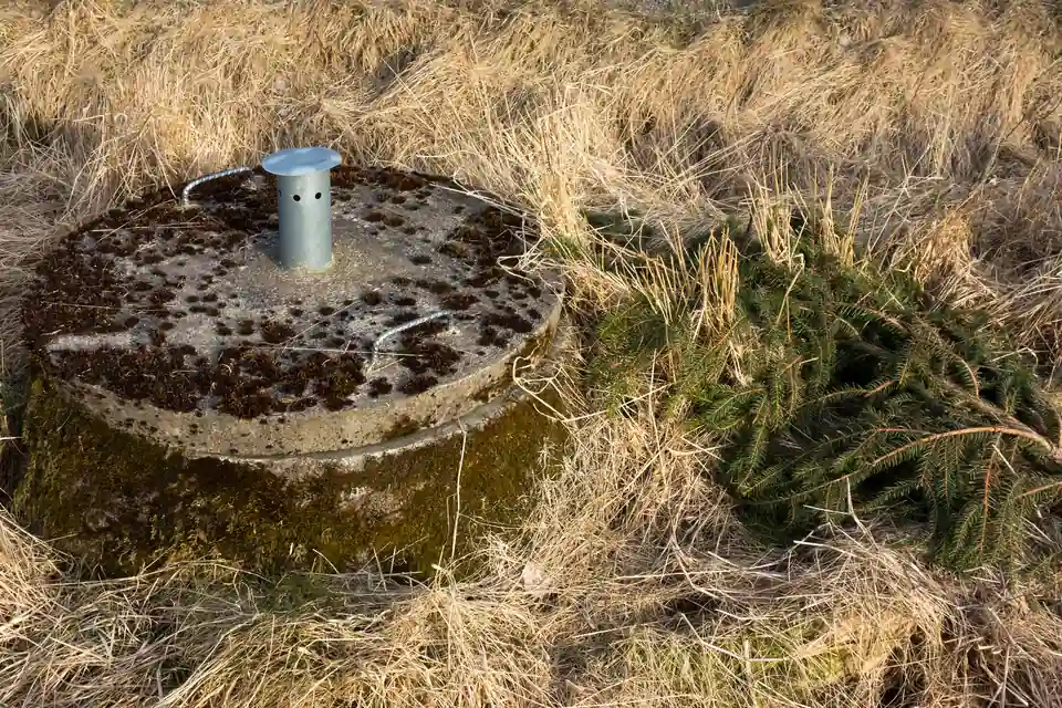 Round concrete septic tank lid with a vent in a grassy rural area.