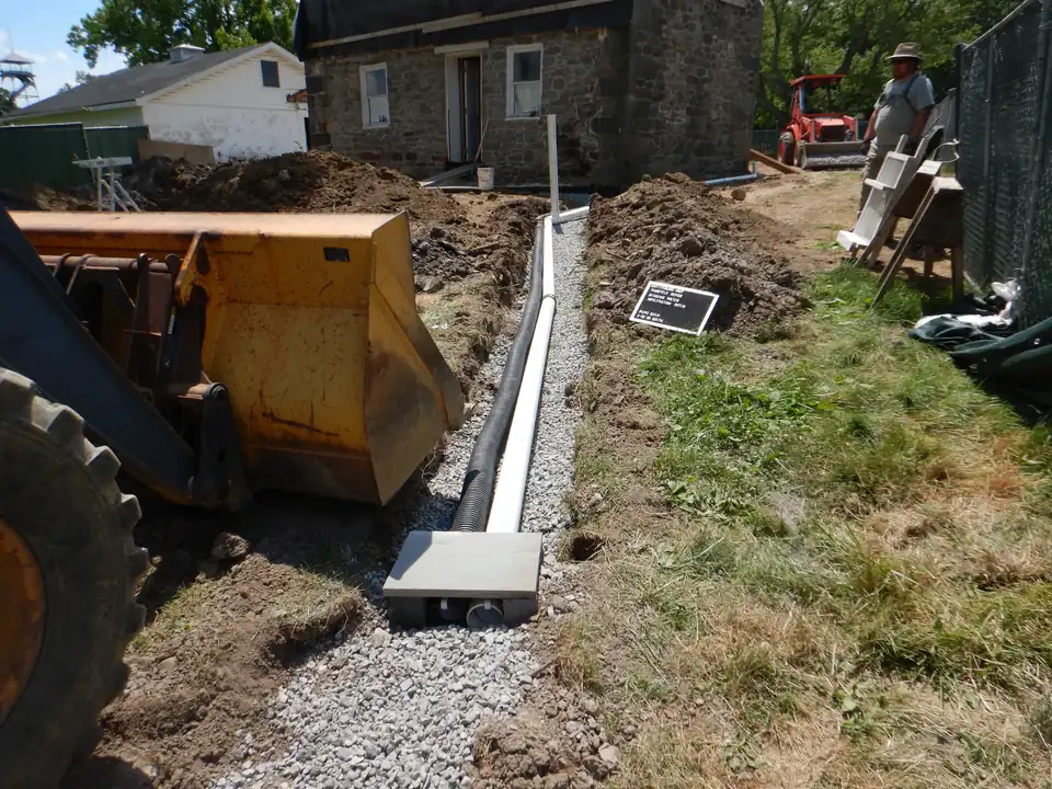 Drainage pipes being installed in an excavated trench to carry water away from a building.