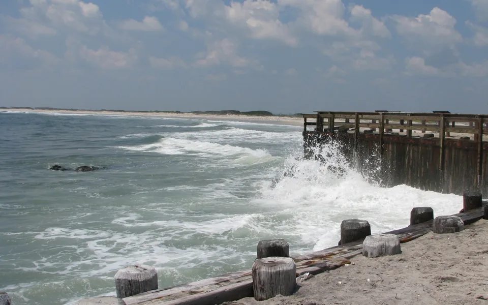 Weathered coastal bulkhead extending along the shoreline at Holgate Beach.